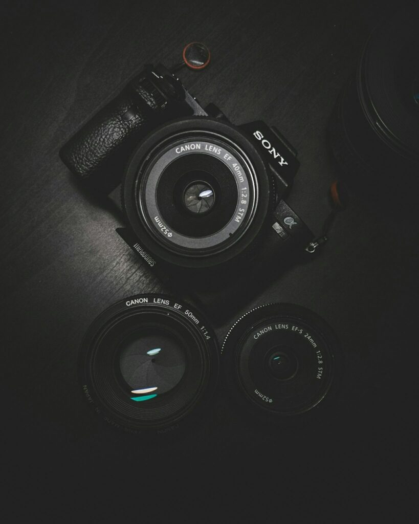 Appareil photo Sony vu de dessus avec un objectif Canon monté, entouré de deux objectifs supplémentaires posés à plat sur une surface sombre